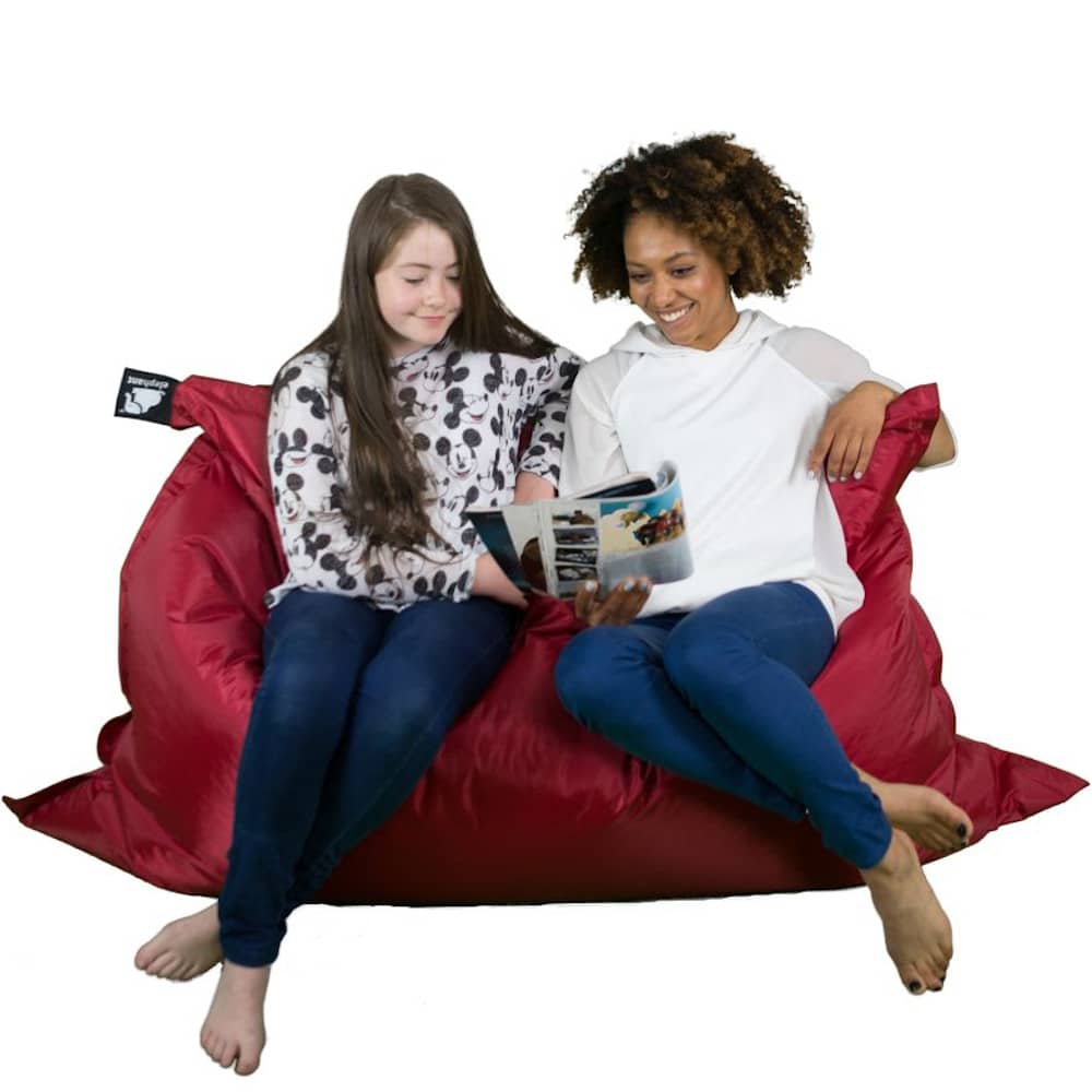 Jumbo vibrant red bean bag with two people sitting on it smiling