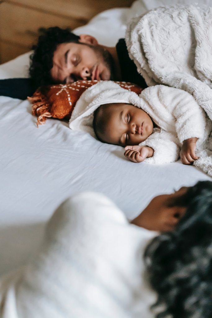 Two parents sleeping next to their child