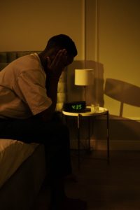 man sitting on the dge of his bed in the dark